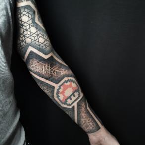 Baybay Blondy, tatoueuse guest à Paris - Bras géométrique réhaussé d’un champignon de Super Mario tatoué par son confrère Bro Vanthorn