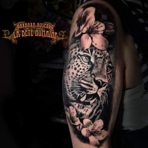 Portrait réaliste de léopard affublé de fleurs tatoué par Barbara Rosendo