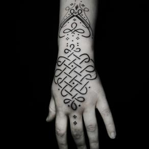 Tatouage symbolique en entrelacs sur la main réalisé par Baybay Blondy